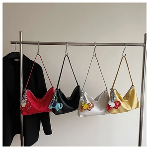 Detail view of four textured leather shoulder bags with colorful elephant charms in assorted colors