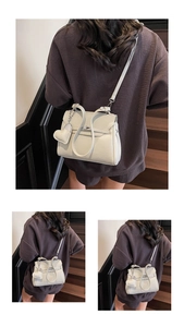 Macro shot of cream lychee texture leather handbag featuring a heart pendant detail