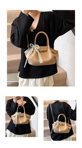 Detail of camel leather handbag with white lace bow, pearl charm and top handle strap
