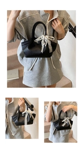 Detail of black leather handbag featuring white lace bow and delicate pearl heart charms
