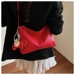 Detail of red pebbled leather hobo bag with elephant charm on model in black blazer