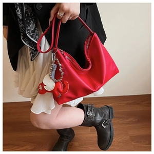 Detail of red pebbled leather tote bag with unique elephant charm and zip closure