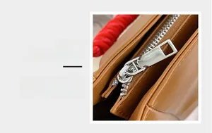 Detail magnification showing smooth silver metal zipper on brown leather tote bag fabric