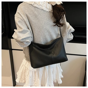 Detail of black lychee grain leather tote bag with soft pleats and long shoulder strap