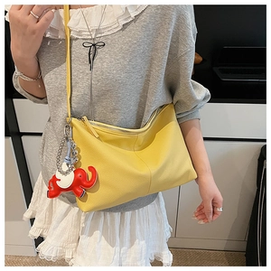 Close-up of yellow pleated dumpling bag with elephant charm and metal zipper detail