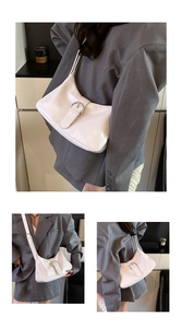 Detail of white glossy leather hobo bag with a prominent silver metal buckle detail
