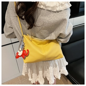 Detail of yellow lychee grain faux leather shoulder bag with a cute red elephant charm
