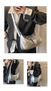 Close-up of a silver hobo bag with metallic texture and buckle detail worn cross-body