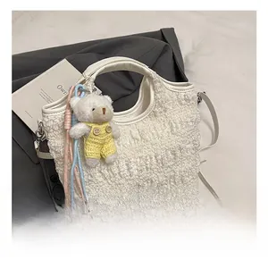 Détail d'un sac seau blanc plissé avec pendentif d'ours et bandoulière amovible