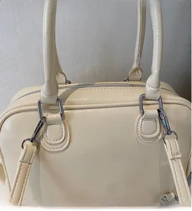 Detail of silver metallic hardware and glossy leather texture on the cream tote bag