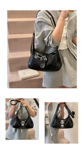 Detail of a black hobo bag with glossy finish and silver horseshoe buckle hardware