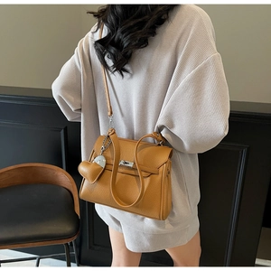 Side view of yellow litchi grain leather handbag with heart charm on a model