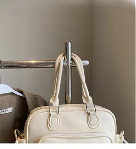Detail of off-white lychee texture tote bag featuring durable handles and silver metal D-rings