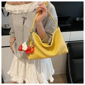 Detail of yellow lychee grain leather hobo bag featuring a unique elephant charm hanging