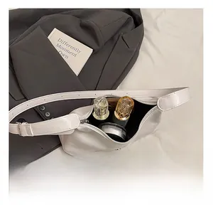 Internal capacity of white pebble leather underarm bag holding phone and perfume