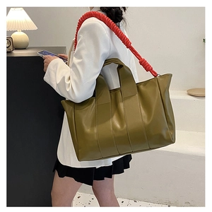 Olive green tote bag with red braided shoulder strap shown on a model for size perspective