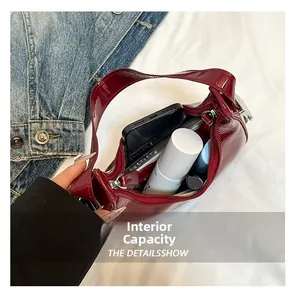 Internal capacity of dark red patent leather shoulder bag showing smartphone and cosmetics