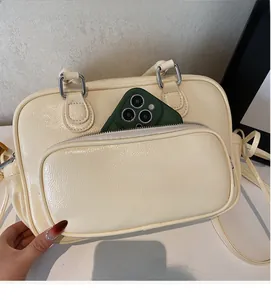Detailed view of the creamy white patent leather bag showing front zipper pocket capacity