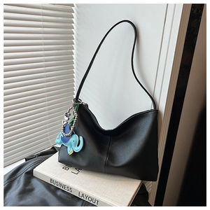 Black pebble leather hobo bag with blue elephant charm on white prop book display