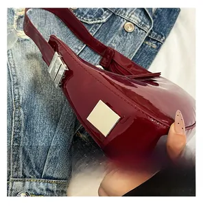 Detail of burgundy patent leather handbag with glossy finish and silver metal accents