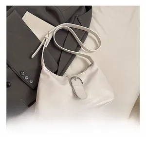 Detail view of a white leather hobo bag with metal buckle on a grey blazer outfit