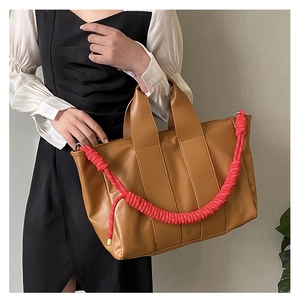 Borsa tote in pelle marrone con tracolla intrecciata rosa vivace mostrata su modella