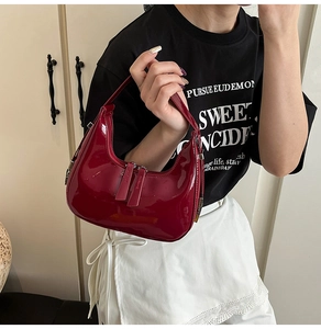 Détail du sac croissant en cuir verni rouge foncé avec fini brillant et double fermeture
