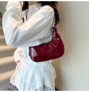 Détail du sac hobo en cuir verni bordeaux avec garniture argentée et pompons zippés