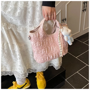 Détail du sac seau rose clair plissé avec texture gaufrée et charm ours en peluche
