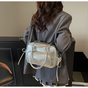 Rear view of silver Boston bag with lychee texture held over a grey blazer jacket