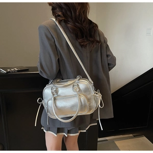 Detail of silver metallic Boston bag with adjustable strap and side drawstring texture
