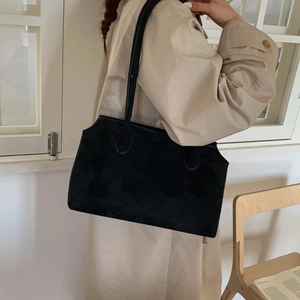 Sac fourre-tout en daim noir porté avec un trench pour un look quotidien chic et élégant