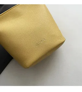Detailed macro view of yellow lychee grain leather texture with CLEARLY logo print