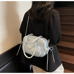 Detail of light blue pebble leather boston bag with side ribbons shown on a model