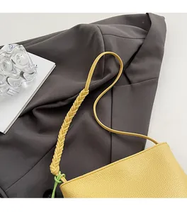 Close-up of pale yellow hobo bag featuring grainy leather and woven shoulder strap detail