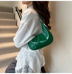 Détail du sac croissant en cuir verni vert avec fermetures éclair argentées et brillant