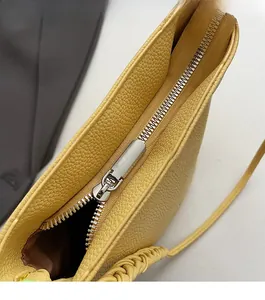 Close-up of bright yellow lychee leather bag with smooth metal zipper and woven strap