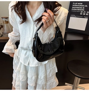 Détail du sac hobo en cuir verni noir brillant avec finitions métalliques argentées