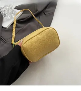 Detail view of the flat bottom and woven handle on this yellow pebble leather bucket bag