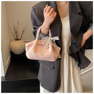 Detailed shot of pink lychee leather handbag with lace bow and pearl pendant charm