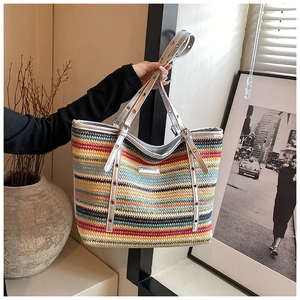 Detail of colorful striped woven tote bag featuring silver handles and metallic eyelets