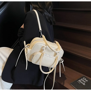 Detail of cream multi-functional crossbody bag with side bow decor and multiple zippers