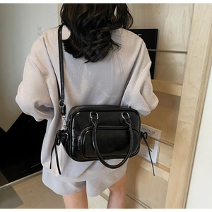 Detail of black glossy faux leather tote with detachable strap and side tassel accents