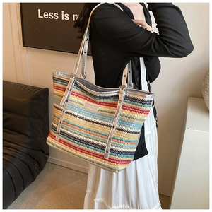 Detail of colorful striped woven tote bag featuring metallic silver strap and hardware