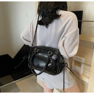 Detail of glossy black patent leather boston bag with knot decor and dual handles