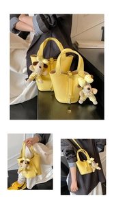 Detail of yellow lychee texture bucket bag with metal lock and cute dog plush pendant
