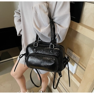 Detail of black patent leather handbag with glossy texture and detachable strap