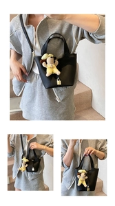 Detailed views of a black litchi pattern bucket bag with golden lock and plush charm