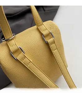 Dettaglio borsa gialla in pelle a grana litchi con fibbie in metallo argento e cuciture precise