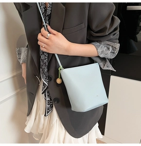 Detail view of light blue lychee pattern leather bucket bag with wooden bead charm